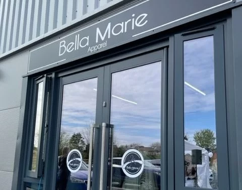 image1-2-rotated-e1719406484928 The exterior of a store named "Bella Marie Apparel" featuring large glass doors. The sign above the entrance displays the store name in white letters against a dark background.